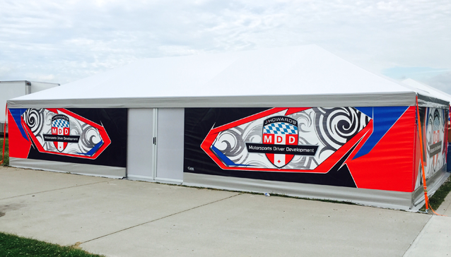 Tenda paddock con pannelli grafici stampati per il team Howard's Motorsports Driver Development: stemma su fondo rosso, blu e nero con motivo grigio a volute.